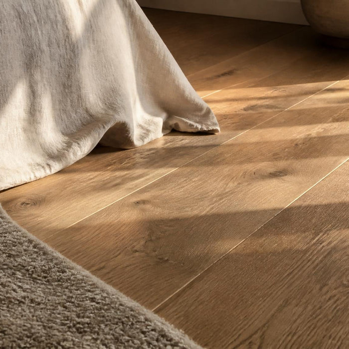 Detail van een houten slaapkamervloer met matte afwerking, houtnerf en zacht vloerkleed.