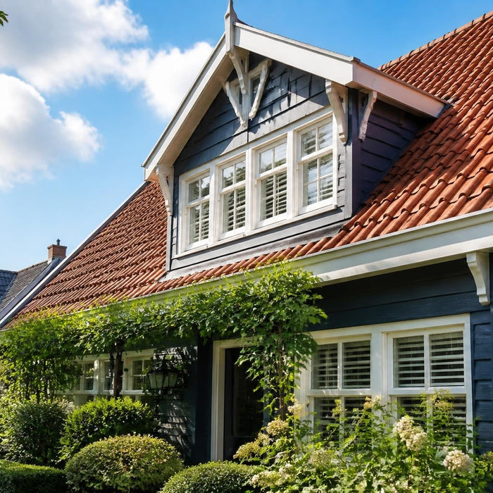 Brede buitenfoto van een nette woning met een strak geschilderde houten dakkapel in warm daglicht.