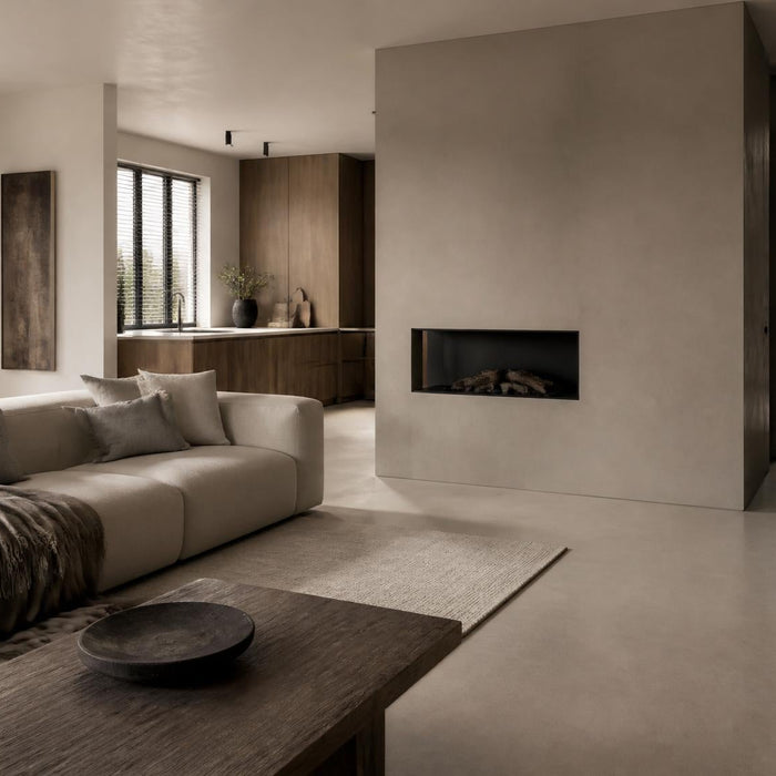 Brede sfeerfoto van een luxe woonruimte met naadloze microcement vloer en wand in warme natuurlijke tinten.