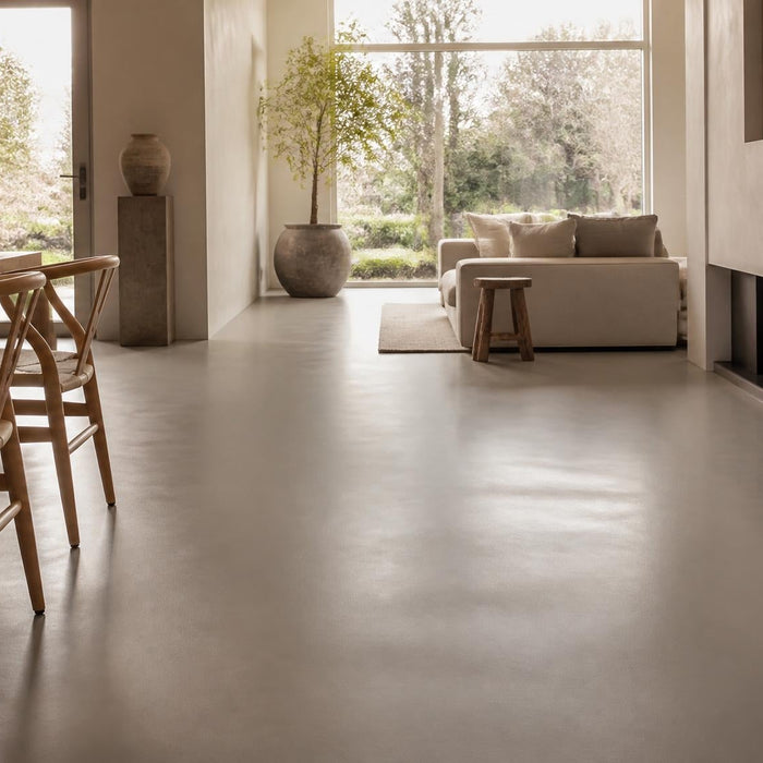 Moderne woonkamer met een strak onderhouden gietvloer in warm daglicht