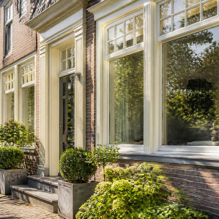 Verzorgde Nederlandse woninggevel met strak geschilderde buitenkozijnen in warm daglicht